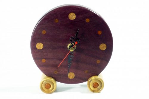Approximately 136mm in diameter. A fine piece of craftsmanship a handmade cheeky wooden clock for the desk, mantle or shelf. This is the real colour of the wood and has not been altered in any way, it will enrich with age. The clock hands are of course RoHS approved and tested and come complete with full instructions. Designed and made by me in Shropshire - not mass produced; each of my Tommy Woodpecker Woodworks clocks is slightly different and unique, beautifully and lovingly finished with beeswax polish so the natural colour of the wood can speak for itself! An ideal gift for anyone who loves the unique richness and quality of the grain and colours of natural finely crafted wooden items. A special, memorable gift for a wedding, anniversary, housewarming, leaving or retirement gift for someone very special. All clocks are carefully packaged to ensure they reach you safely and have labels and care instructions, ideal for any gift. 1 x AA Battery operated, battery included for UK only not included for overseas, batteries cannot be airmailed. Care Instructions To set the time, do not push the hands of the clock around, use the white dial on the back of the clock mechanism to alter the time. To dust the clock, avoid damaging the hands by gently dusting one half of the clock face at a time, when the hands are clear of the area, then repeat for the other half of the clock face when the hands are clear of that area. The battery can be taken out for cleaning to stop the clock at any time. Occasionally a slightly damp cloth can be used if necessary. The wood will benefit from a little gentle application of beeswax once a year and will reward you with a continued shine.